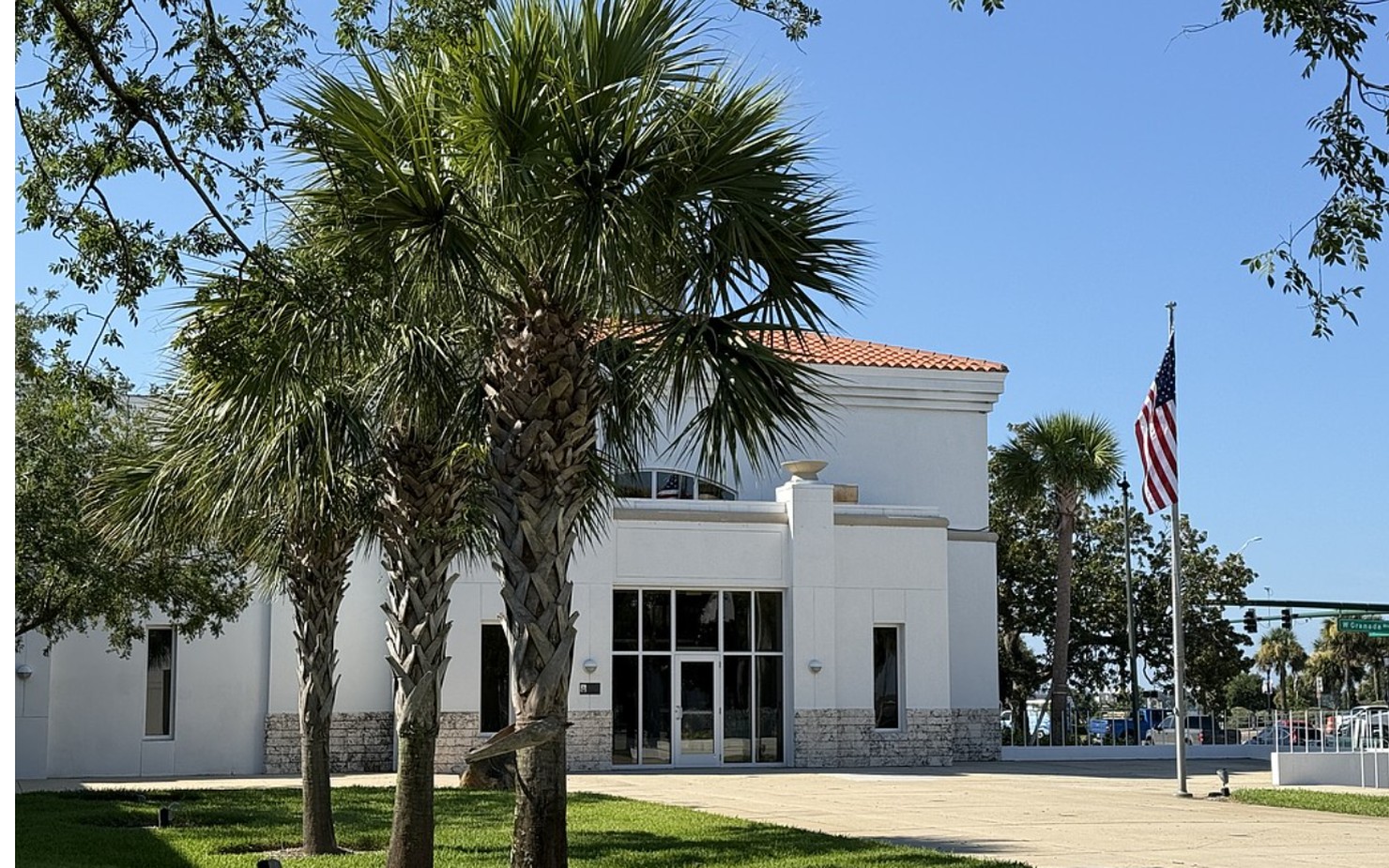 Ormond Beach City Hall framed by palm trees, with an American flag flying out front.